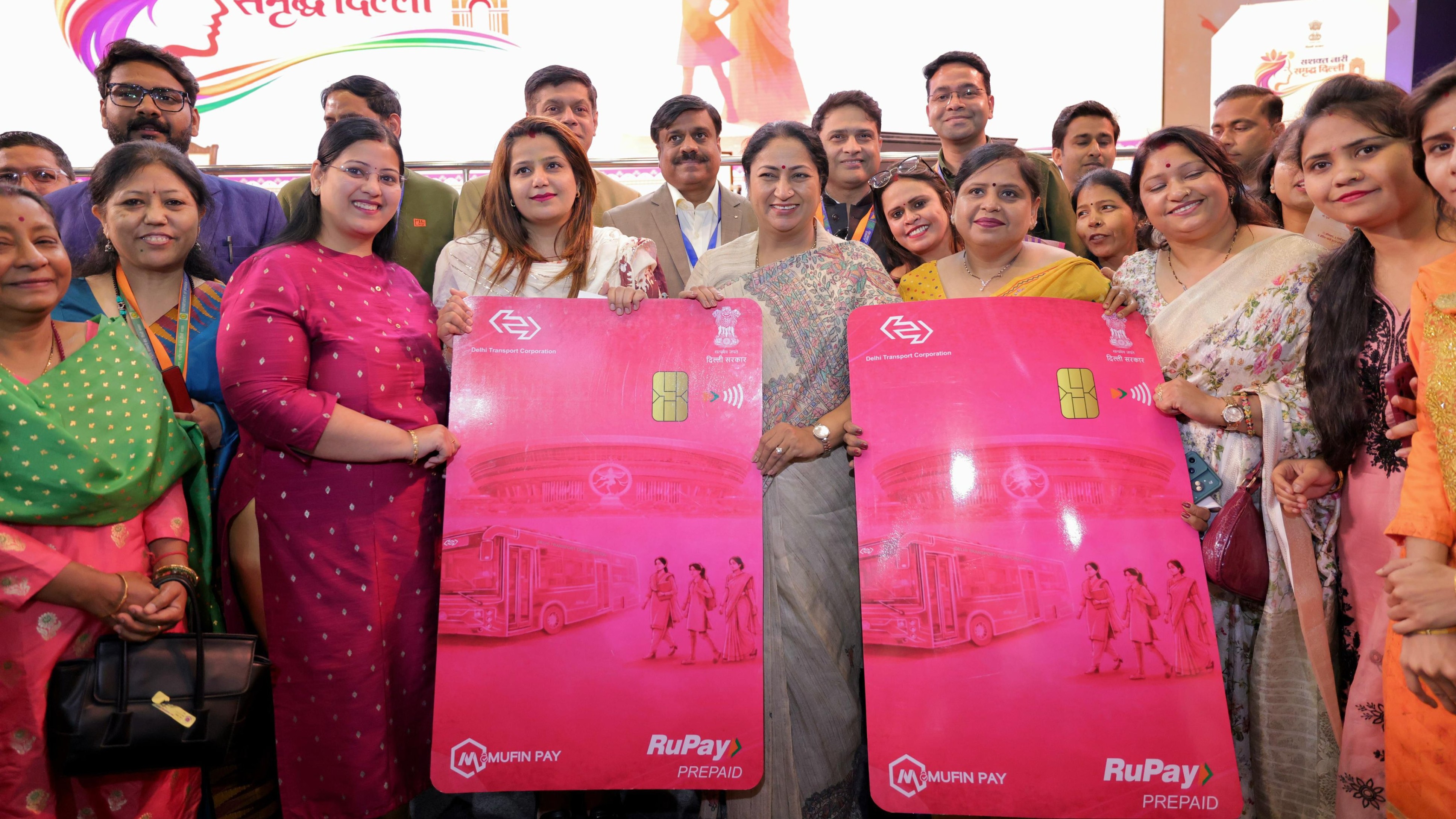 A Delhi Transport Corporation bus beside a pink smart mobility card and a card reader.