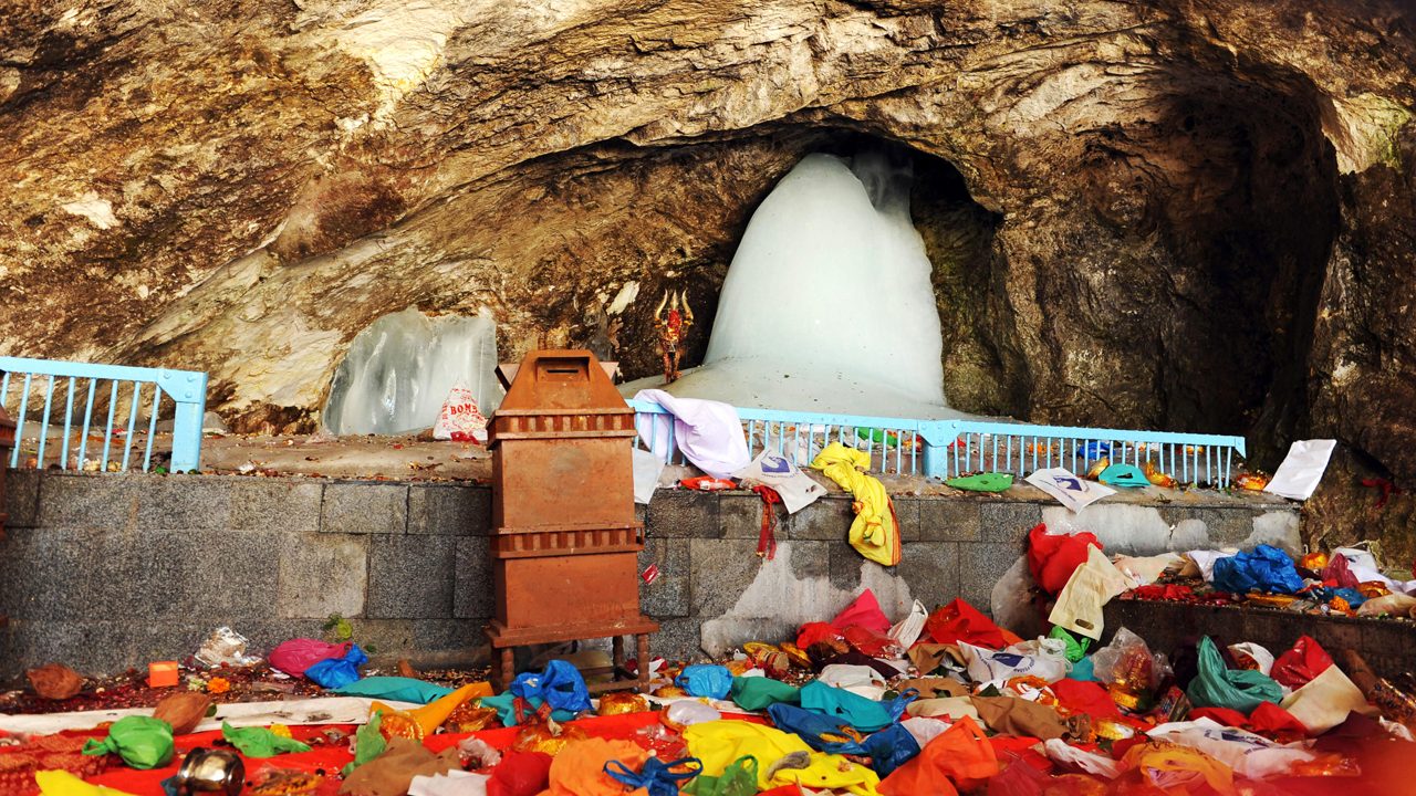 Pilgrims on the Amarnath Yatra route in Jammu and Kashmir with support workers and mountain terrain.