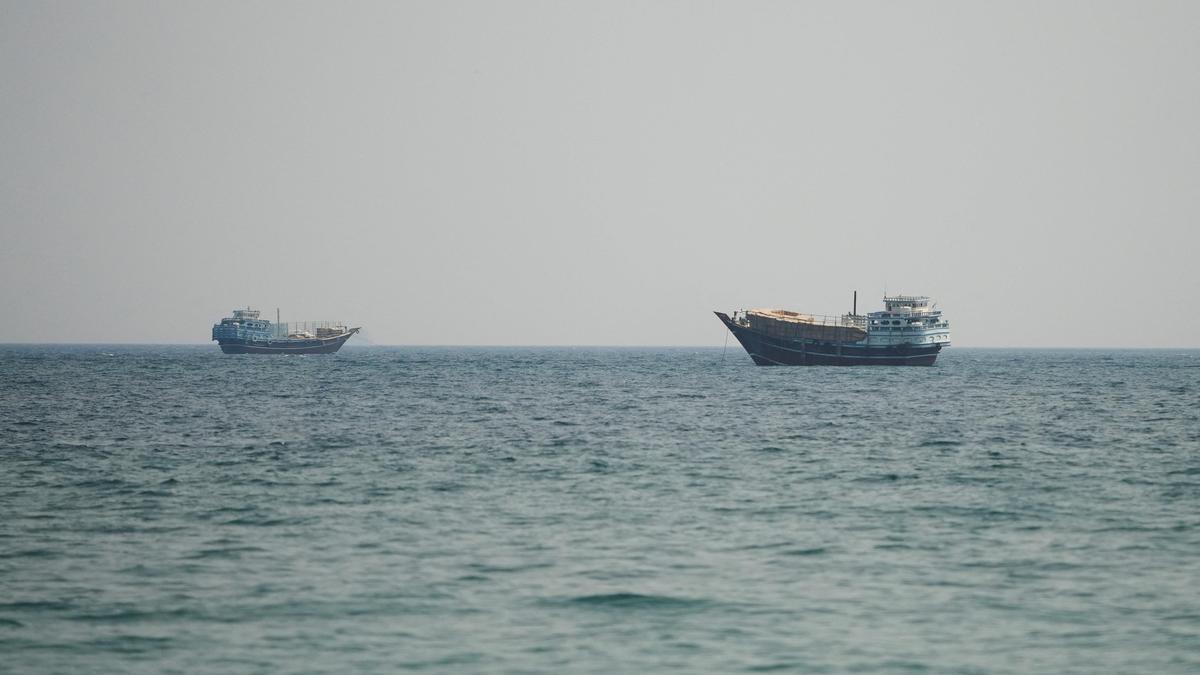 A narrow maritime strait with one cargo tanker, coastal radar installations, and missile launchers onshore.